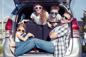 family posing in back of car