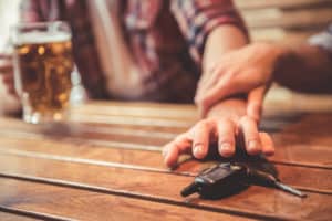 image of drunk man talking car keys and his friend stopping him