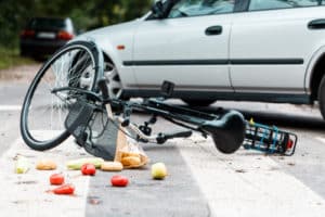 Crashed bike lying on the street near a car after traffic accident 300x200 1