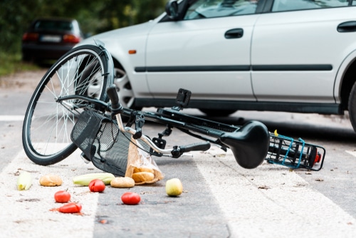 Crashed bike lying on the street near a car after traffic accident