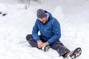 Man holding his leg in pain while sitting in snow after bike accident in Colorado