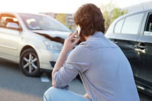 Man kneels beside his car after a wreck in Boulder, CO