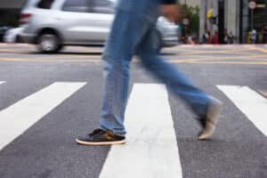 A cropped shot of a man walking through a crosswalk