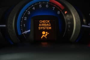 A close-up shot of a car dashboard that says "Check Airbag System"
