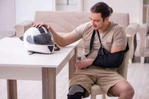 A man with a broken arm from a motorcycle accident in Colorado sitting next to his helmet
