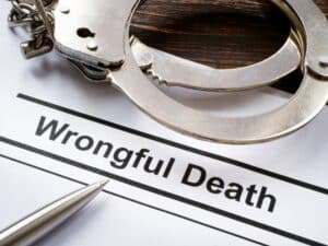 Handcuffs on a table with a piece of paper that says "Wrongful Death"