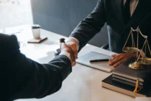 A victim of legal malpractice shaking an attorney's hand