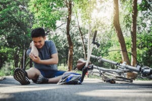 Man sitting on the ground after a right-hook bicycle accident in Boulder